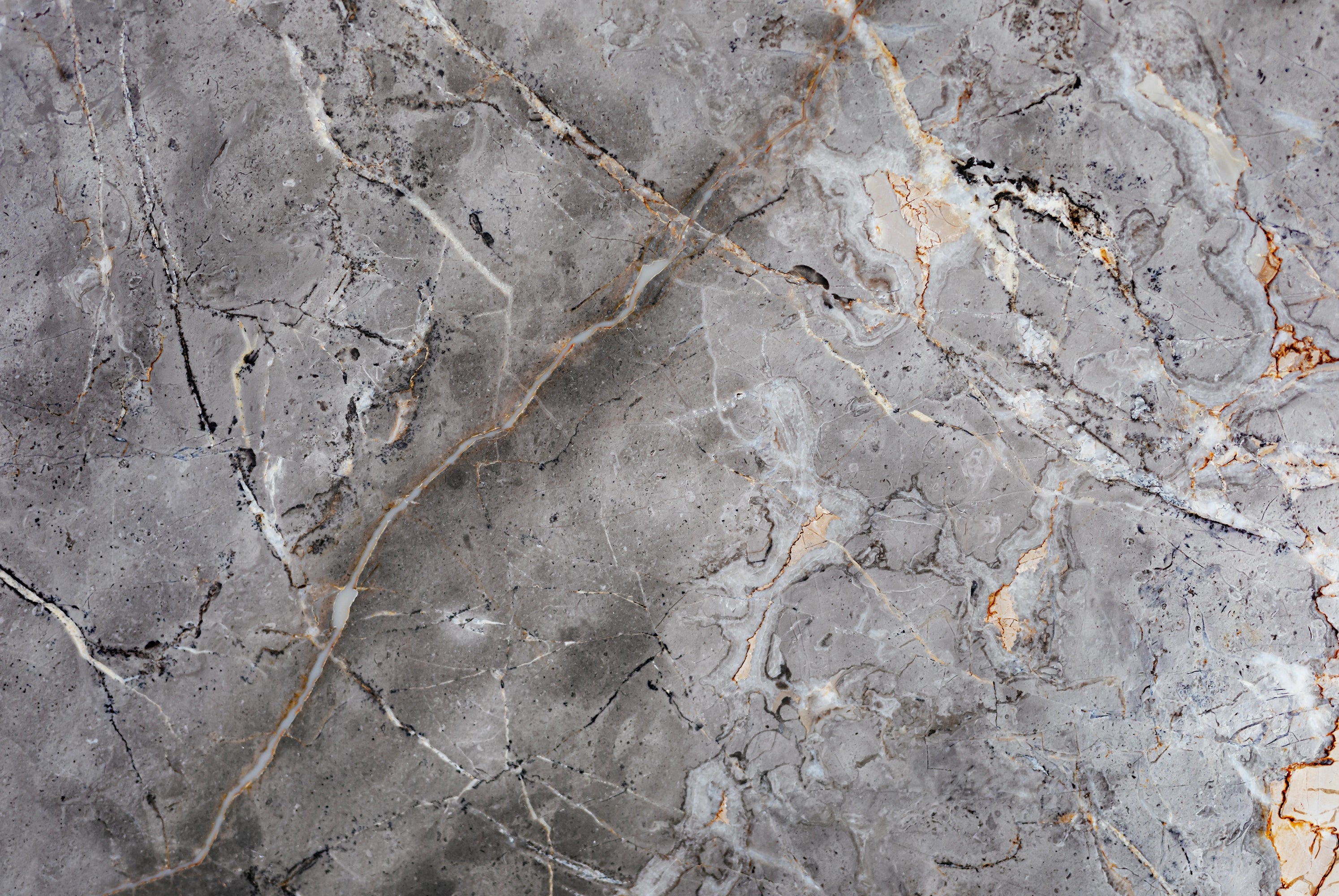 FX‑142 Iron Vein Marble flexible marble panel featuring a cool mid‑grey base streaked with bold white and rust‑orange veins, accented by fine iron‑speckled textures for an industrial yet elegant look, by Dunya Home Design.