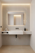 Modern bathroom vanity with illuminated mirror and tiled walls.