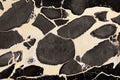 FX‑127 Midnight Pebble Marble flexible marble panel showcasing large irregular midnight-black pebble shapes embedded in a soft cream matrix with fine textural details, by Dunya Home Design.