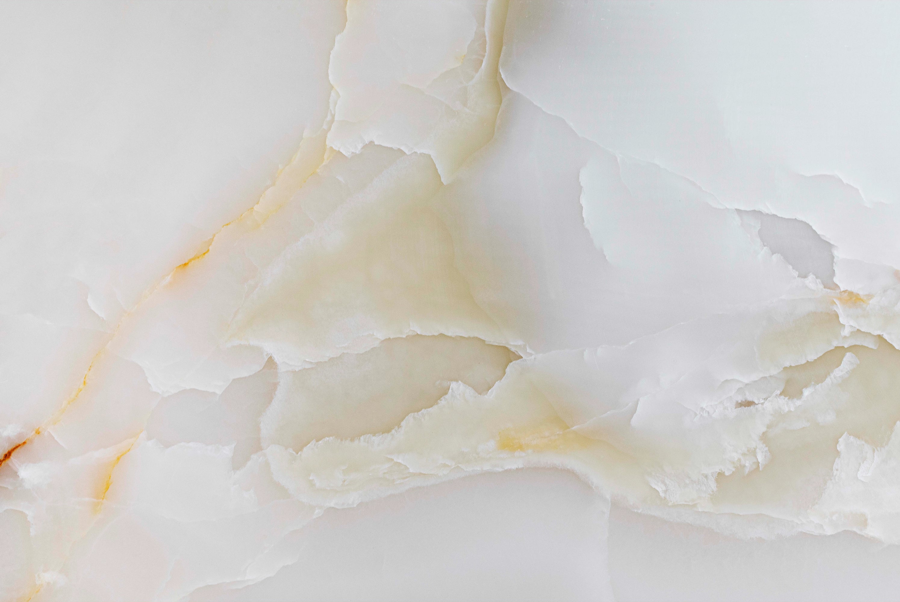 FX‑137 Golden Dawn Marble flexible marble panel showcasing luminous white and pale cream onyx layers with gentle golden-yellow highlights and soft translucent textures, by Dunya Home Design.
