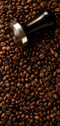 Marble mural of dark textured surface surrounded by coffee beans and espresso-making tools, evoking rich coffee tones